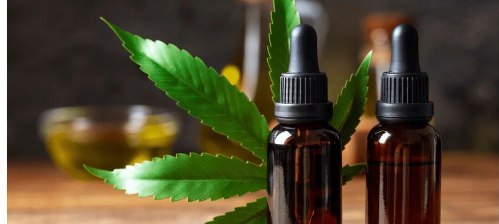 Frascos de vidro âmbar com conta-gotas e folhas de cannabis sobre fundo de madeira, representando cosmética natural com canabinoides para cuidados da pele.