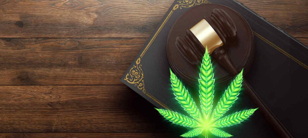 “Mazza giudiziaria e libro di leggi accanto a una foglia di cannabis, a simboleggiare la regolamentazione legale e il quadro giuridico degli avvocati specializzati in cannabis