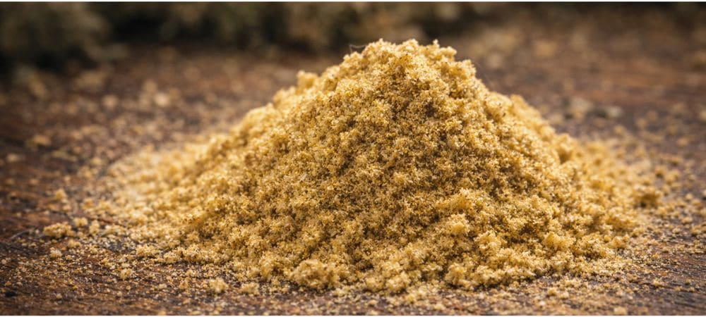  Polen rubio de cannabis separado tras el proceso artesanal de tamizado en seco sobre superficie de madera
