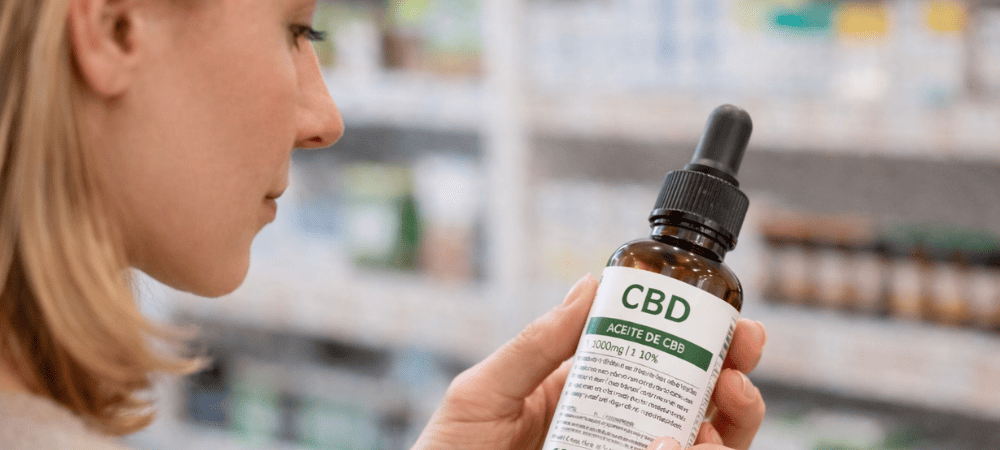 Mujer comprobando la etiqueta de de un aceite CBD